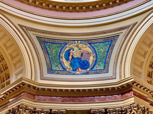 Mural on a ceiling depicting a seated figure with a book, surrounded by decorative foliage and intricate patterns.