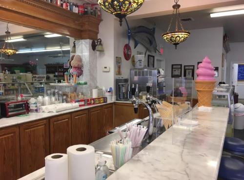 A vintage ice cream shop counter with a pink ice cream cone, straws, and a soda fountain in a bright, inviting space.