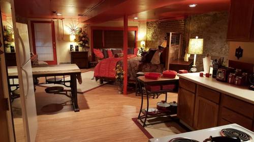 Cozy basement apartment featuring a kitchen, dining area, and a bedroom with red accents and warm lighting.