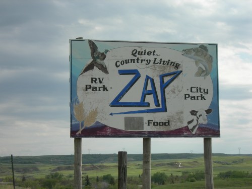 Sign for Zap, featuring "Quiet Country Living," with icons for RV Park, City Park, and food options.