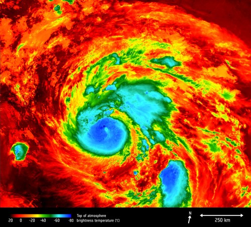 Satellite image of a hurricane, showing swirling clouds in vibrant colors, with temperature scale and distance markers.