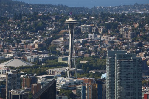Aerial view of Seattle featuring the Space Needle surrounded by urban buildings and greenery.