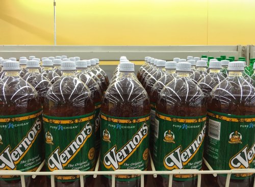 Bottles of Vernors ginger soda lined up on a store shelf, featuring a green label and "Pure Michigan" branding.