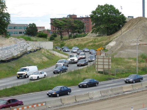 Traffic congestion on a highway with multiple vehicles and construction debris in the background.