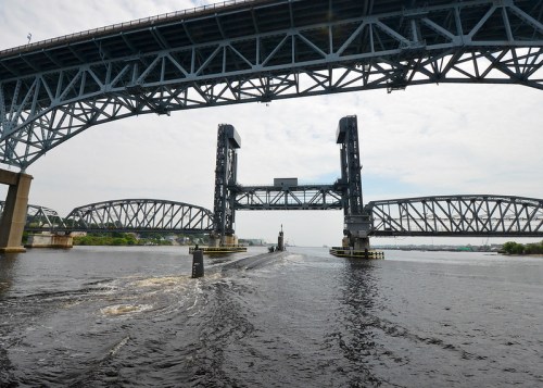 A view of two large, raised bridges over a river, with a submarine passing beneath them.