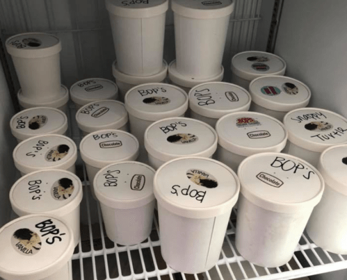 A freezer filled with labeled containers of ice cream, including flavors like vanilla and chocolate.