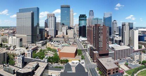 A panoramic view of a vibrant city skyline with modern skyscrapers and clear blue skies.