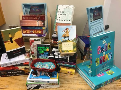 A colorful display of various books stacked and arranged, featuring titles like "A Tree Grows in Brooklyn" and "The Book of Books."