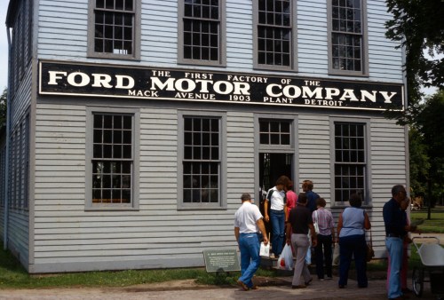 Visitors gather outside the historic Ford Motor Company factory building in Detroit, showcasing its iconic sign.