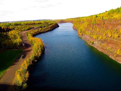Aerial view of a winding river surrounded by colorful autumn foliage and steep, rocky banks.