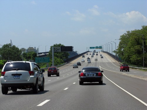 A busy highway with multiple lanes, cars traveling in both directions under a clear blue sky.