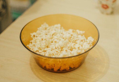 A bowl of freshly popped popcorn on a wooden table.