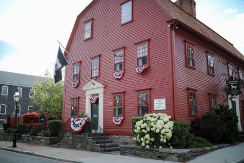 Historic red building adorned with bunting and flowers, set against a clear sky.
