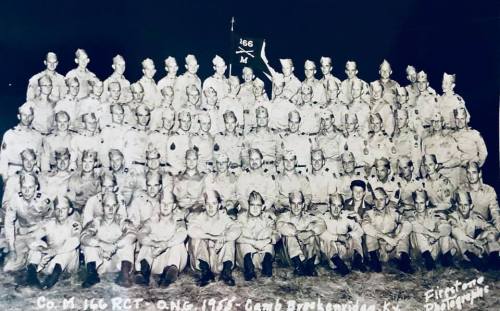 A large group photo of soldiers in uniform, arranged in rows, with a banner reading "Co. M 166 RCT" in the background.