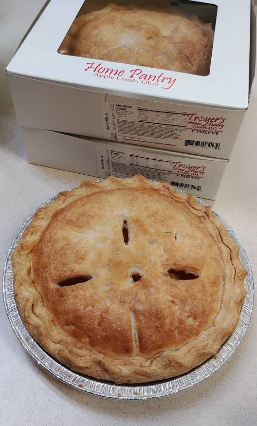 A freshly baked apple pie in a silver tin, with two boxes labeled "Home Pantry" in the background.