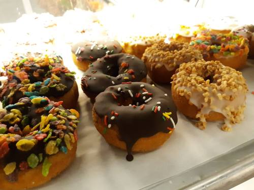 A variety of colorful donuts with chocolate, sprinkles, and toppings displayed in a case.