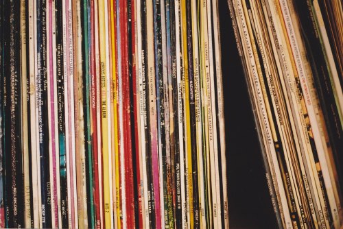 A close-up of colorful vinyl record spines arranged closely together on a shelf.