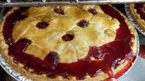 A freshly baked cherry pie with a golden crust and a glossy red filling, cooling on a rack.