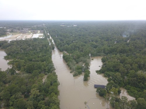 Aerial view of a flooded area with trees and roads submerged in water, showcasing extensive flooding in a rural landscape.