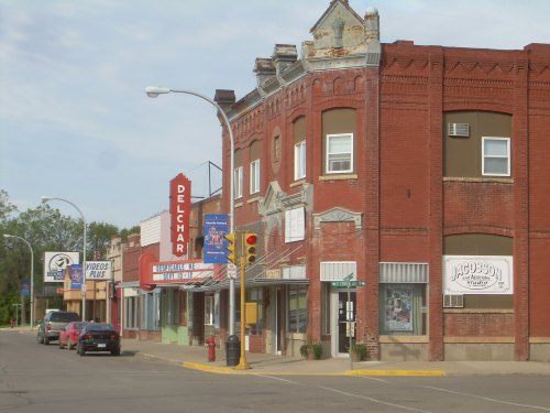 A small town street featuring brick buildings, a theater marquee, and a video rental store.