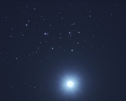 A night sky filled with stars, featuring a bright celestial object radiating light at the bottom.