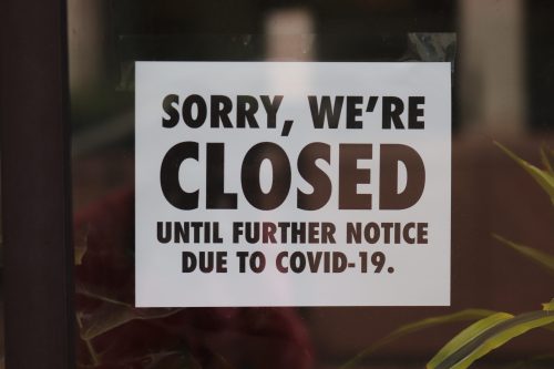 A sign on a door reads, "Sorry, we're closed until further notice due to COVID-19."