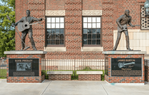 Statues of Elvis Presley and James Burton on brick pedestals, with plaques detailing their contributions to music.