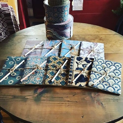 A collection of beautifully patterned notebooks tied with twine, arranged on a wooden table.