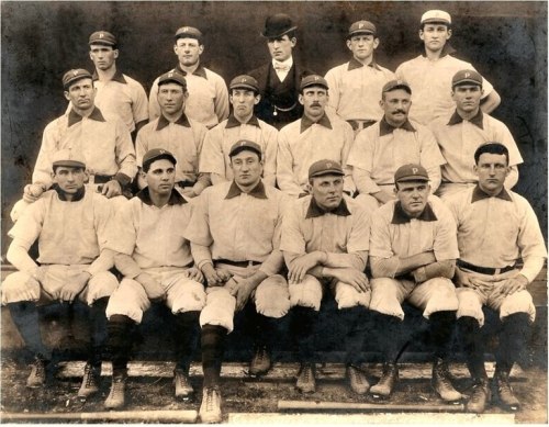A vintage black-and-white photo of a baseball team, featuring players in uniforms and caps, posed together.