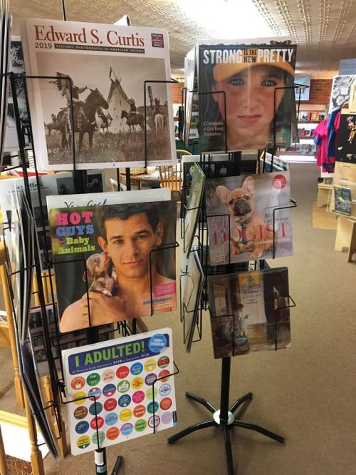 A display rack featuring various magazines, including "Edward S. Curtis," "Strong is the New Pretty," and others.