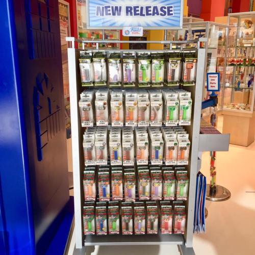 Display of various colorful products on a shelf labeled "New Release" in a bright store setting.