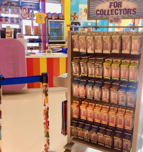 Display of collectible items in a colorful store, featuring various packaged figures and a vibrant background.