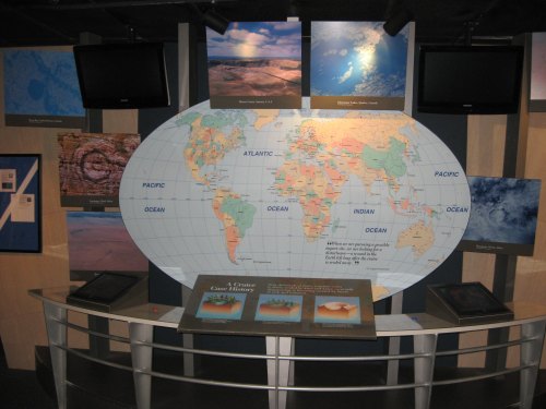 A world map displayed in an exhibit, surrounded by informational panels and screens about oceans and geography.
