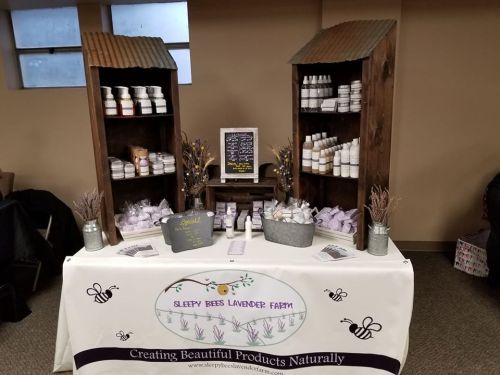 Display of lavender products at Sleepy Bees Lavender Farm, featuring shelves of jars and a decorative tablecloth.