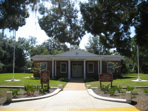 Exterior view of the Gorrie Museum, featuring a brick building with a front pathway and green landscaping.