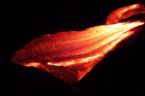 Lava flows glowing brightly in the dark, showcasing swirling patterns and intense heat.