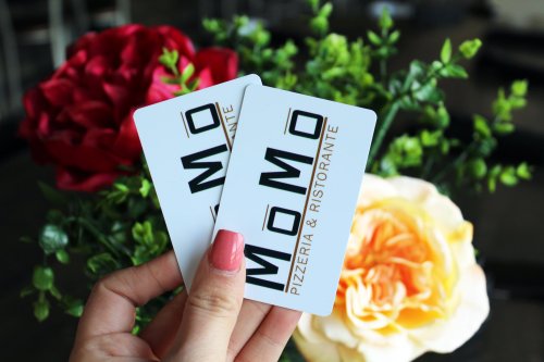 Two loyalty cards for Momo Pizzeria & Ristorante held above a bouquet of flowers.