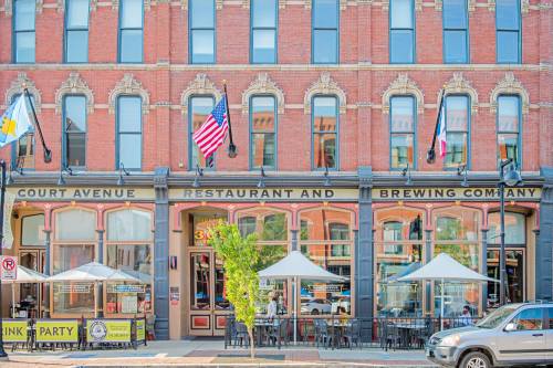 Exterior of Court Avenue Restaurant and Brewing Company, featuring outdoor seating and American flags on a sunny day.