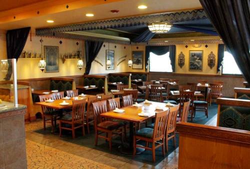Cozy restaurant interior with wooden tables, chairs, and decorative wall art, featuring a warm, inviting atmosphere.