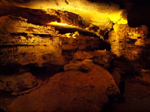 A dimly lit cave interior with rocky formations and illuminated walls, creating a mysterious atmosphere.