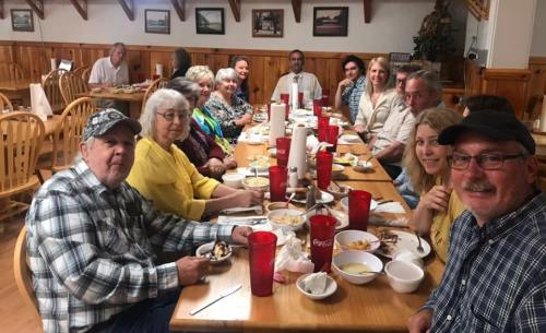 A group of people enjoying a meal together at a long table in a cozy restaurant.