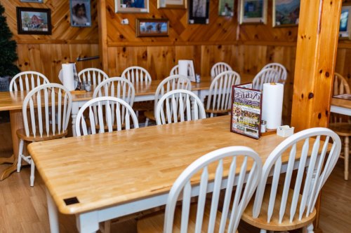 A cozy restaurant interior with wooden tables and white chairs, featuring rustic decor and a menu on the table.