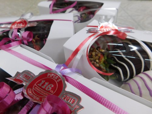 Boxes of chocolate-covered treats with decorative ribbons, celebrating Piper's 116th anniversary, 1903-2019.