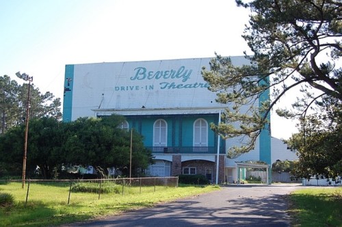 A vintage drive-in theater building with "Beverly Drive-In Theatre" painted on the side, surrounded by trees.