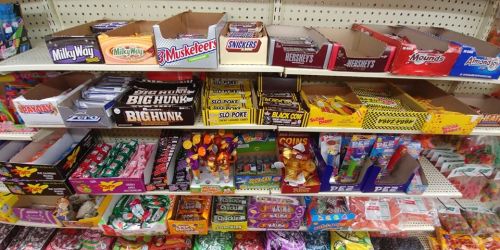 A colorful display of various candy bars and snacks on shelves, including Milky Way, Snickers, and PEZ dispensers.