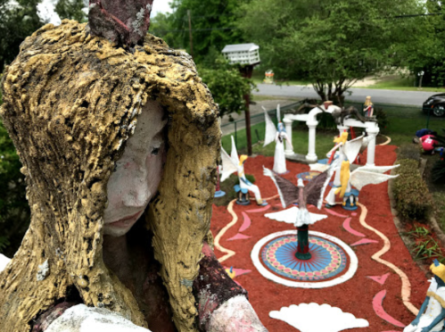 A colorful outdoor garden featuring whimsical sculptures and a central circular design, viewed from above.