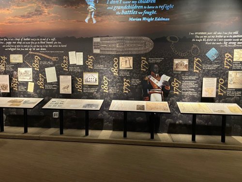 Exhibit featuring historical documents and artifacts, with a quote by Marian Wright Edelman on a backdrop of a crowd.