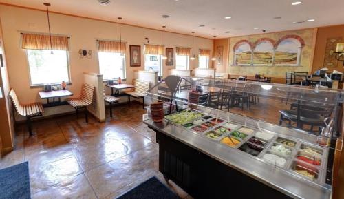 Interior of a casual dining restaurant featuring a salad bar and seating areas with large windows and artwork on the walls.