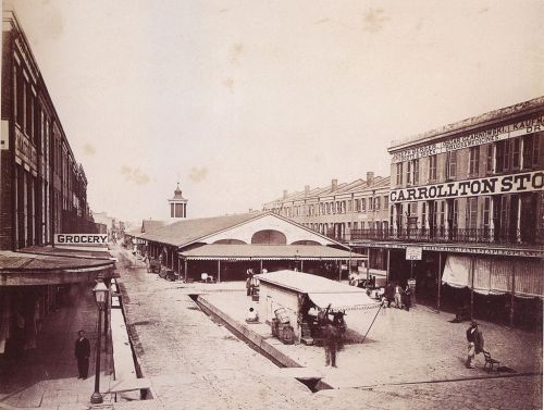 Historic street scene featuring a market, shops, and people in a bustling urban setting.