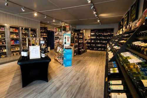 A well-organized wine shop interior with shelves of bottles, display cases, and a central table.